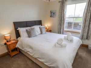 a bedroom with a large white bed with towels on it at Home Stead Cottage in Embleton
