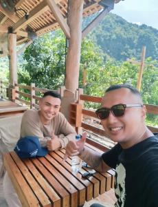 two men sitting at a wooden bench with thumbs up at Dua Bidadari Villa in Cikanteh