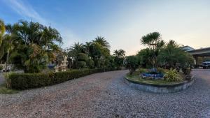 a gravel driveway with palm trees and a building at The Longhouse Luxury Boutique Resort in Sakon Nakhon