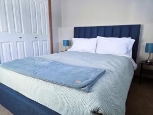 a bed with a blue headboard and white pillows at Quaint Lonsdale Suite in Red Deer