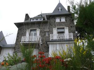 ein altes Backsteinhaus mit einem Balkon und Blumen in der Unterkunft Appartement ROCK WILL in Dinard