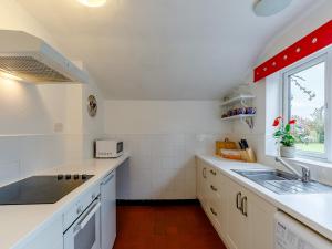 a white kitchen with a sink and a window at Hall Farm Bungalow in Shirley