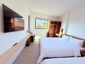 a hotel room with two beds and a flat screen tv at The SunHill in Da Lat
