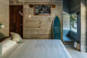 a bedroom with a bed with a surfboard on the wall at Casa TO - Adults Only in Puerto Escondido