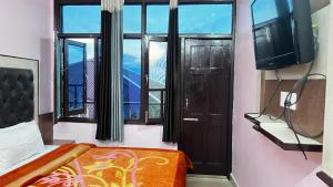 a bedroom with a bed and a window and a tv at Krishna Holiday Guest House in Dharmsāla