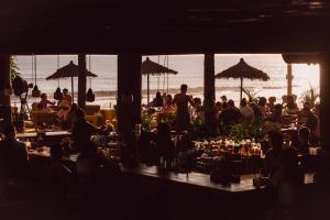 a group of people sitting at tables at the beach at Desa Potato Head Bali in Seminyak