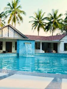 a swimming pool in front of a house with palm trees at SRK luxe resort in Maivādi Road