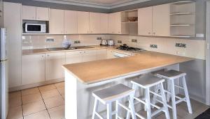 a kitchen with white cabinets and a counter with stools at Sussex Shores in Sussex Inlet
