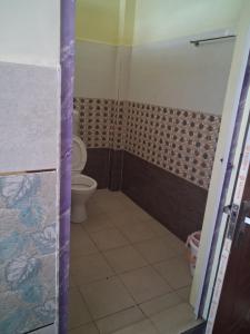 a bathroom with a toilet and a tiled floor at Balaji Inn in Vellore
