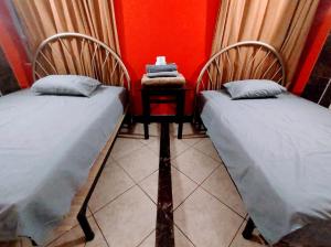 two beds in a room with a side table at Hospedaje ANDRES & COCHERA in San Antonio +3 photos