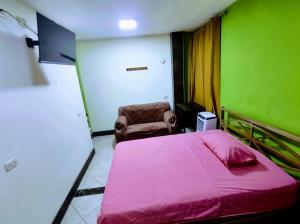 a bedroom with a pink bed and a chair at Hospedaje ANDRES & COCHERA in San Antonio