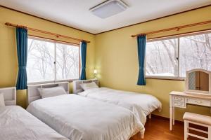 two beds in a room with two windows at holidayhouse SERENADE in Nasu