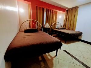 a room with two beds and a table with a window at Hospedaje ANDRES & COCHERA in San Antonio