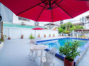 a patio with a table and chairs and a red umbrella at Vientiane Villa Ruby Hotel in Vientiane