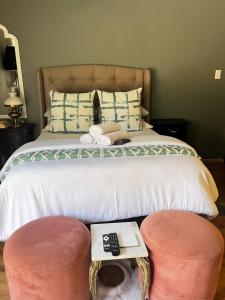 a bedroom with a bed with two ottomans and two chairs at Bird Song in Roodepoort