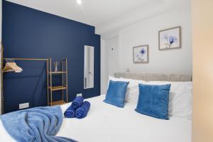 a bedroom with a blue accent wall and a bed with blue pillows at The Quayside Apartments - Central, Steps to Gloucester Quays, Parking and Smart TV in Gloucester
