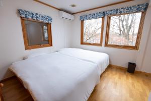 a bedroom with two white beds and two windows at Lilla nasu in Nasu