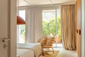 a bedroom with a bed and two chairs in front of a window at Les Roches Rouges, a Beaumier hotel in Saint-Raphaël