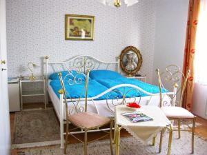a bedroom with a blue bed with two chairs and a table at Hiša Koražija in Rogaška Slatina