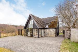 a home with a stone building with a fence at Inshcraig in Kincraig