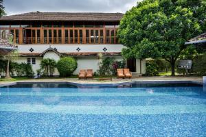 a swimming pool with two chairs and a building at Springdale Heritage in Thekkady