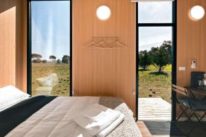 a bedroom with a bed and a view of a field at Little Haven Cottage X by Tiny Away in Balliang