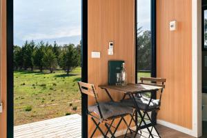 a table and chairs on a porch with a view of a field at Little Haven Cottage X by Tiny Away in Balliang