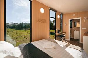 a bedroom with a bed with a large window at Little Haven Cottage X by Tiny Away in Balliang