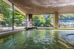 an indoor swimming pool with a view of the trees at KAMENOI HOTEL Akita Yuze in Kazuno