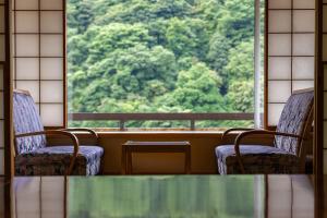 a table and two chairs in front of a window at KAMENOI HOTEL Akita Yuze in Kazuno