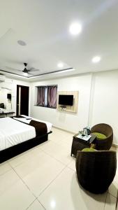 a bedroom with a bed and a tv and chairs at Innzoy Comforts - Hitech City Hyderabad in Hyderabad
