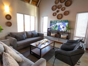 a living room with two couches and a tv at Ntoma House in Hoedspruit