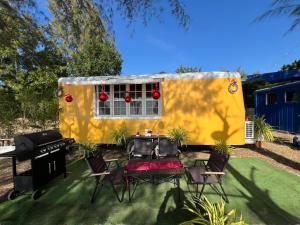 a yellow trailer with a table and chairs in a yard at Sea and Sea Villa Sangaroon in Ban Nam Tok