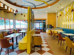 a restaurant with tables and chairs and a restaurant with yellow walls at Coconut Beach Resort, Koh Chang in Ko Chang