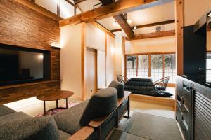 a living room with a couch and a tv at Miyama Ouan in Takayama
