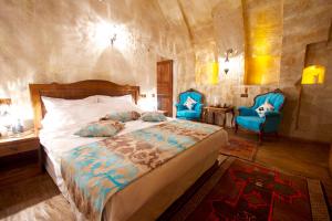 a bedroom with a bed and two blue chairs at Hikmet's House in Avanos