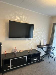 a living room with a flat screen tv on the wall at Sochi A double bed Room in a nice home in Upper Hutt +3 photos