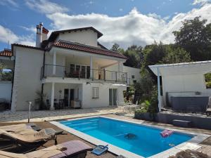 a villa with a swimming pool in front of a house at Apartment für 4 Personen mit Jacuzzi und Pool in Lovran