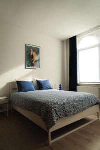 a bedroom with a bed with blue pillows and a window at Lyves Two in Liège