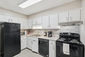 a kitchen with white cabinets and a black refrigerator at Comfort & Convenience in Stone Mountain in Stone Mountain