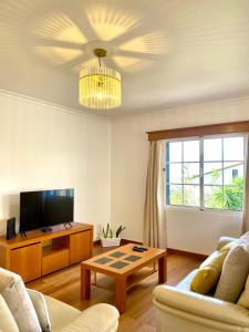 a living room with a couch and a tv and a table at "Fifi House" in Estreito da Calheta
