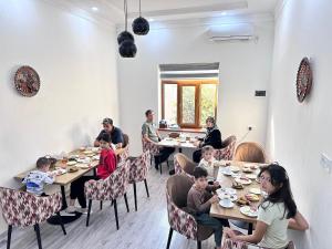 a group of people sitting at tables in a restaurant at Al Fayz Boutique in Bukhara