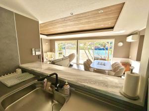 a kitchen with a sink and a living room at Waterfront Hideaway in Miyazaki