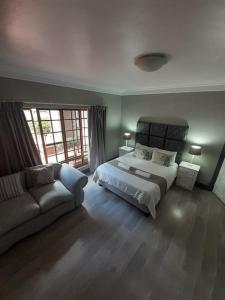 a large bedroom with a bed and a couch at Oakwood Lodge in Bloemfontein