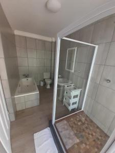 a bathroom with a tub and a toilet and a sink at Oakwood Lodge in Bloemfontein +38 photos