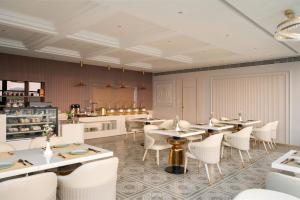 a dining room with white tables and white chairs at Grandala Suites - A Boutique Hotel in Cochin