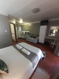 a large white bed in a bedroom with a living room at Oakwood Lodge in Bloemfontein
