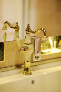 a bathroom sink with a gold faucet and a mirror at Agava Tbilisi in Tbilisi City