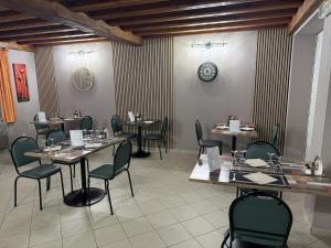 a dining room with tables and chairs and a clock on the wall at Hôtel La Renaissance in Arlanc