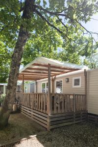 a cabin with awning on a deck next to a tree at Chez gaby in Lagorce